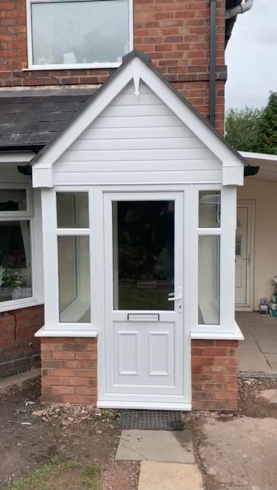 White uPVC porch on a red brick house with brick base columns