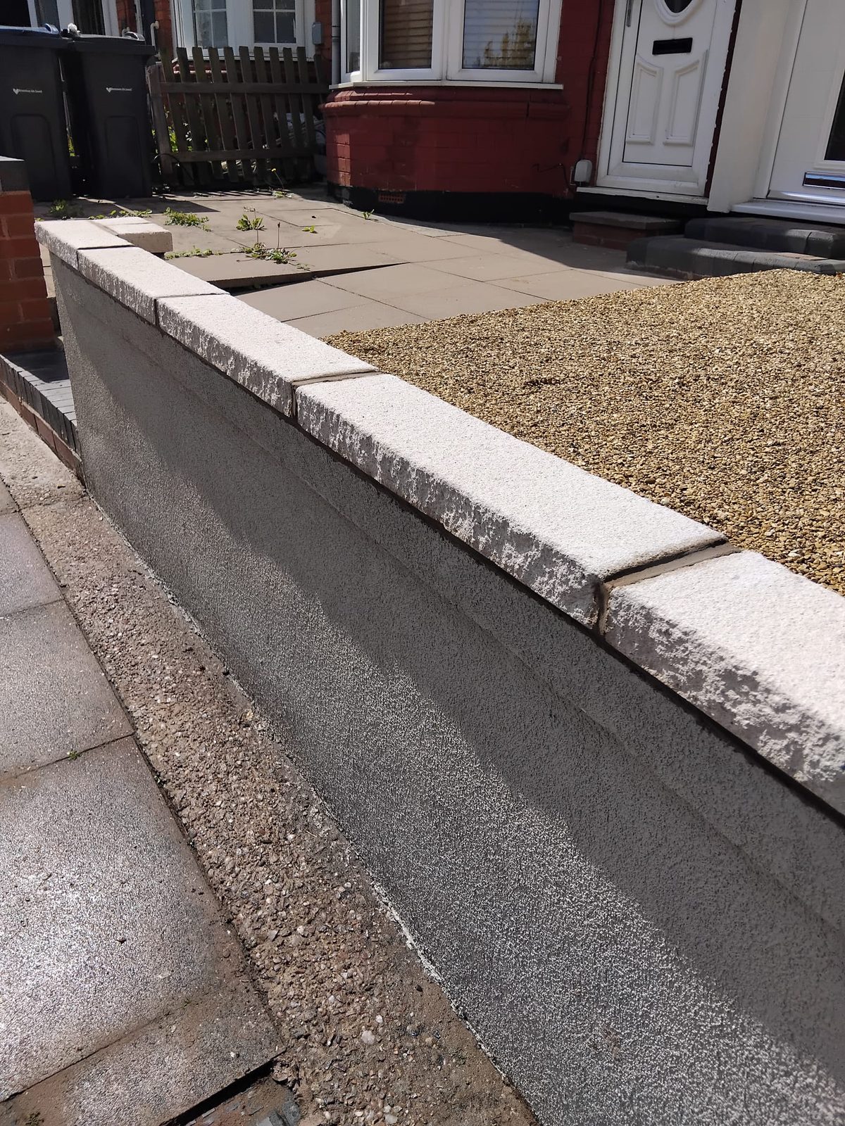 Red brick garden wall with coping stones up to a house