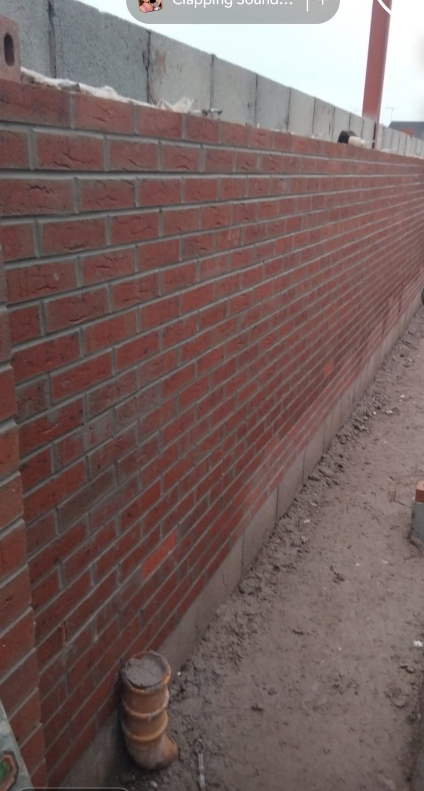 Long red brick wall running along a walkway