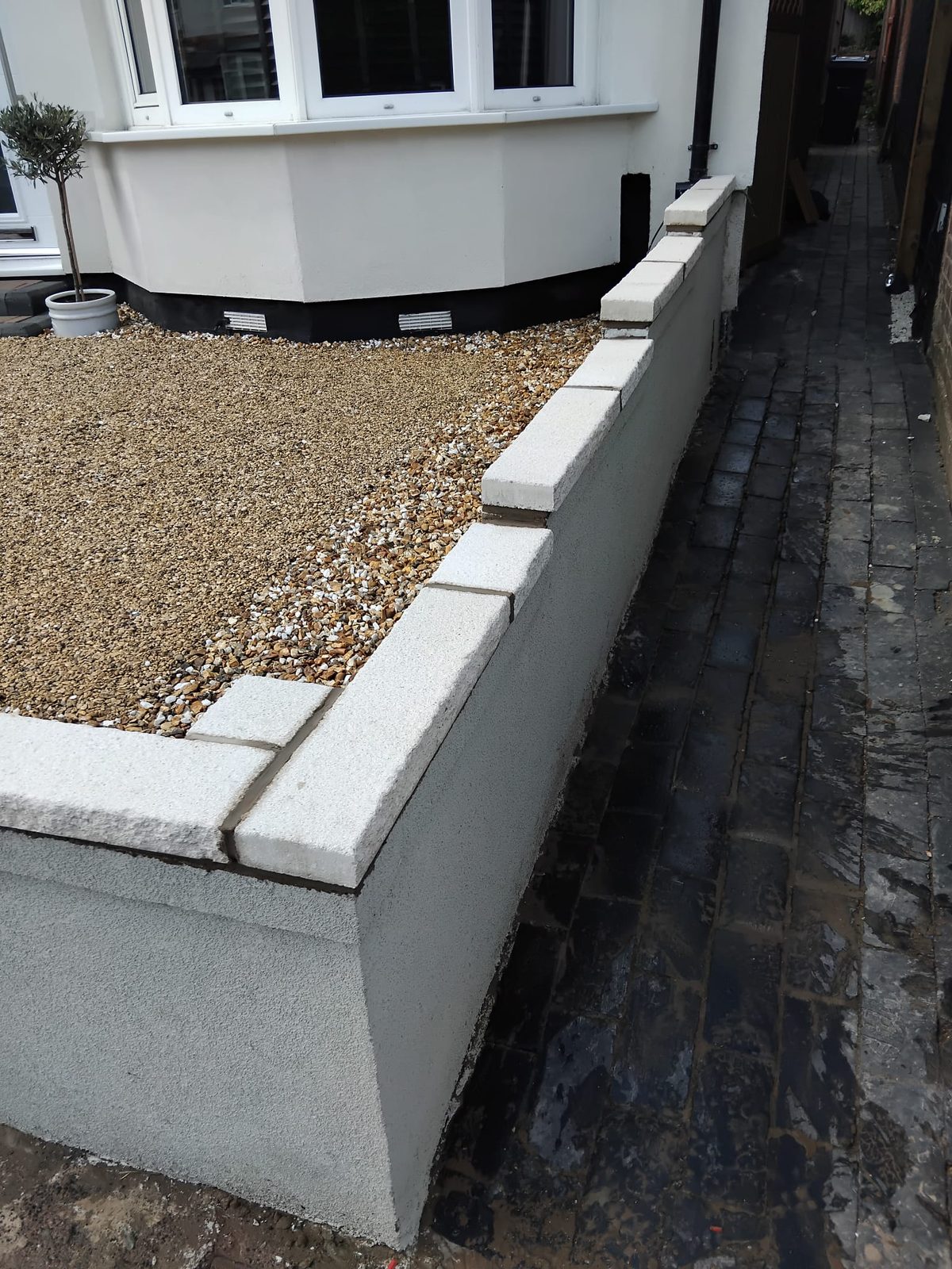 Rendered block garden wall with gravel and dark fence
