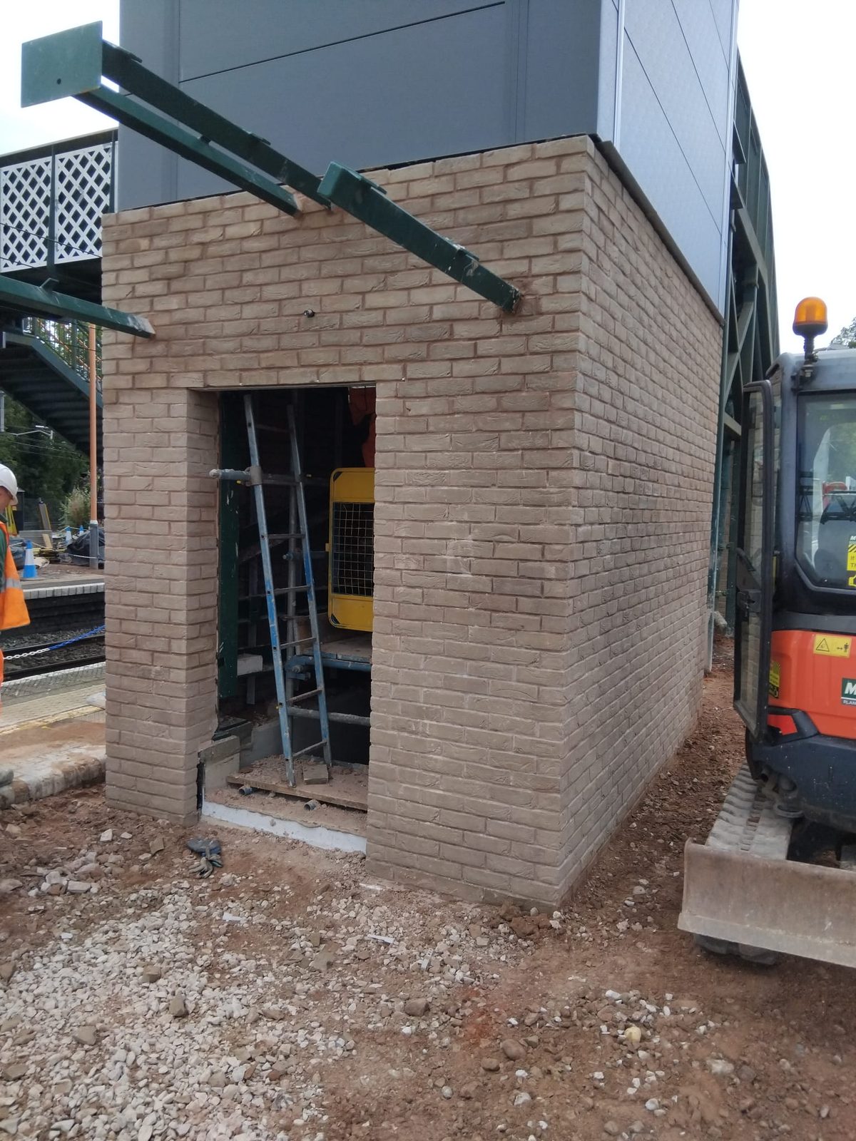 Brick garage build in progress with excavator on site
